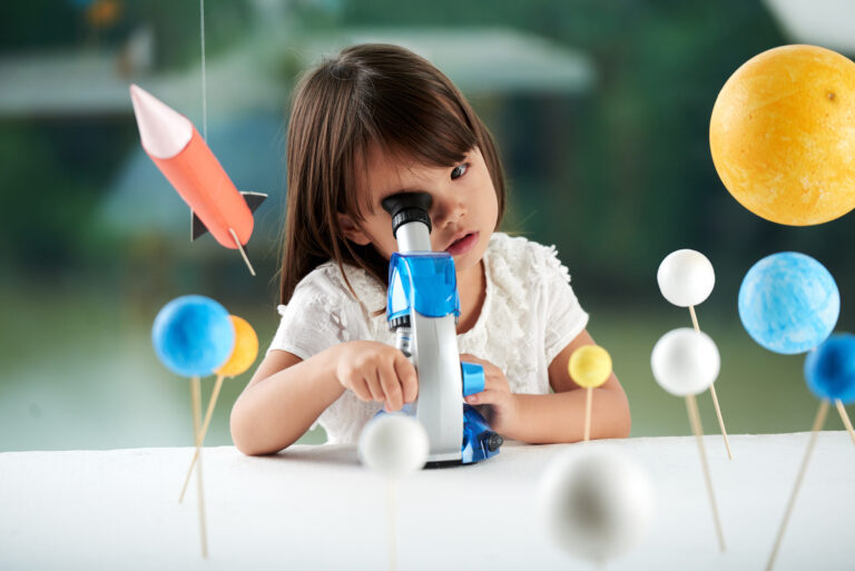 dziewczynka patrzy przez mikroskop
