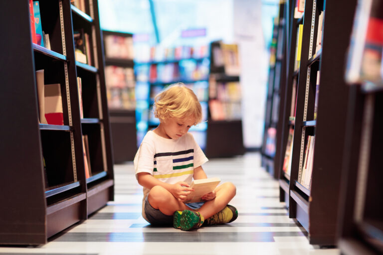 chłopiec czyta książki w bibliotece