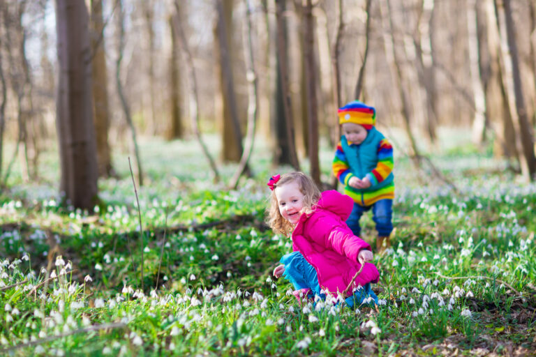 dziewczynka i chłopiec obserwują przebiśniegi – pierwsze zwiastuny wiosny